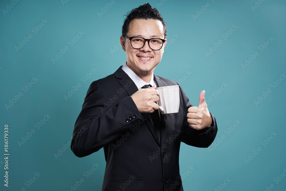 Businessman in suit smile and enjoy cup of coffee with thumb up gesture.