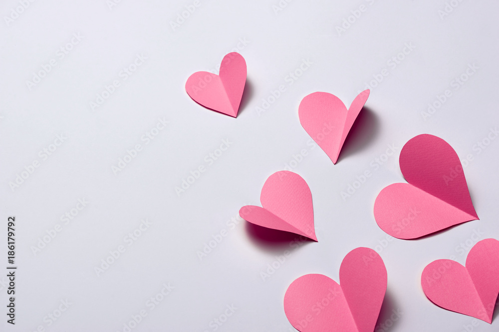 Beautiful pink paper hearts on white paper background