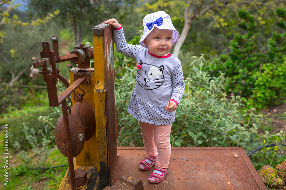 Little girl standing on the old scale in the orange garden of Crete, Greece