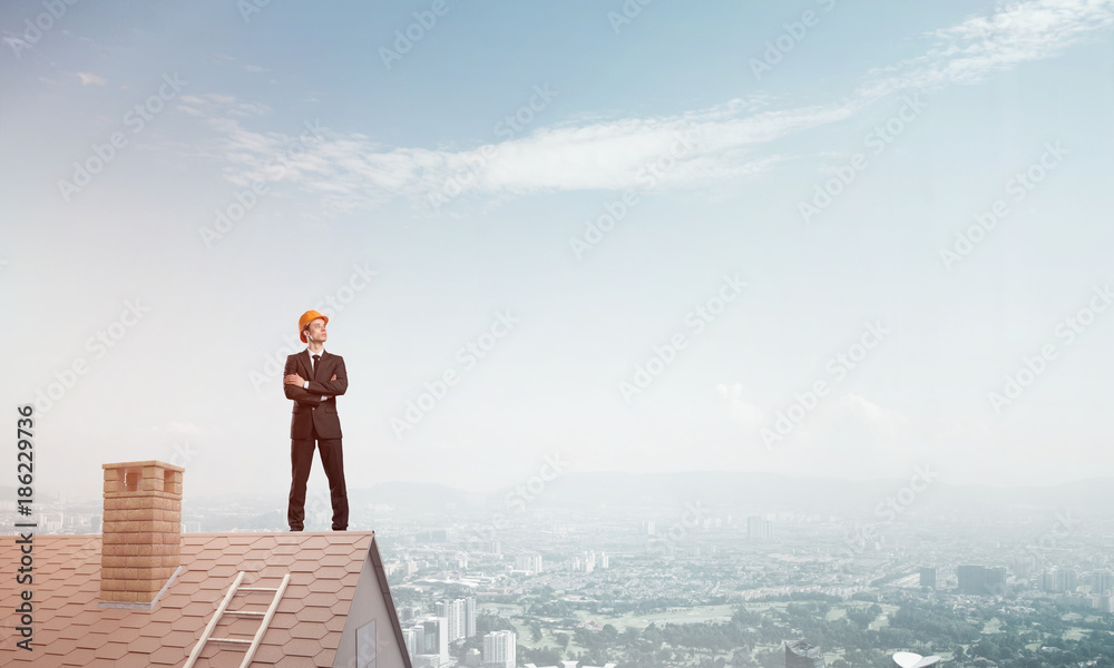 Engineer man standing on roof and looking away. Mixed media