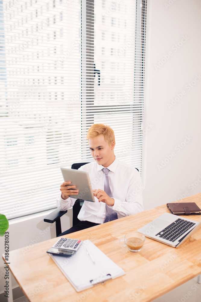 Smiling young man using digital tablet in the office