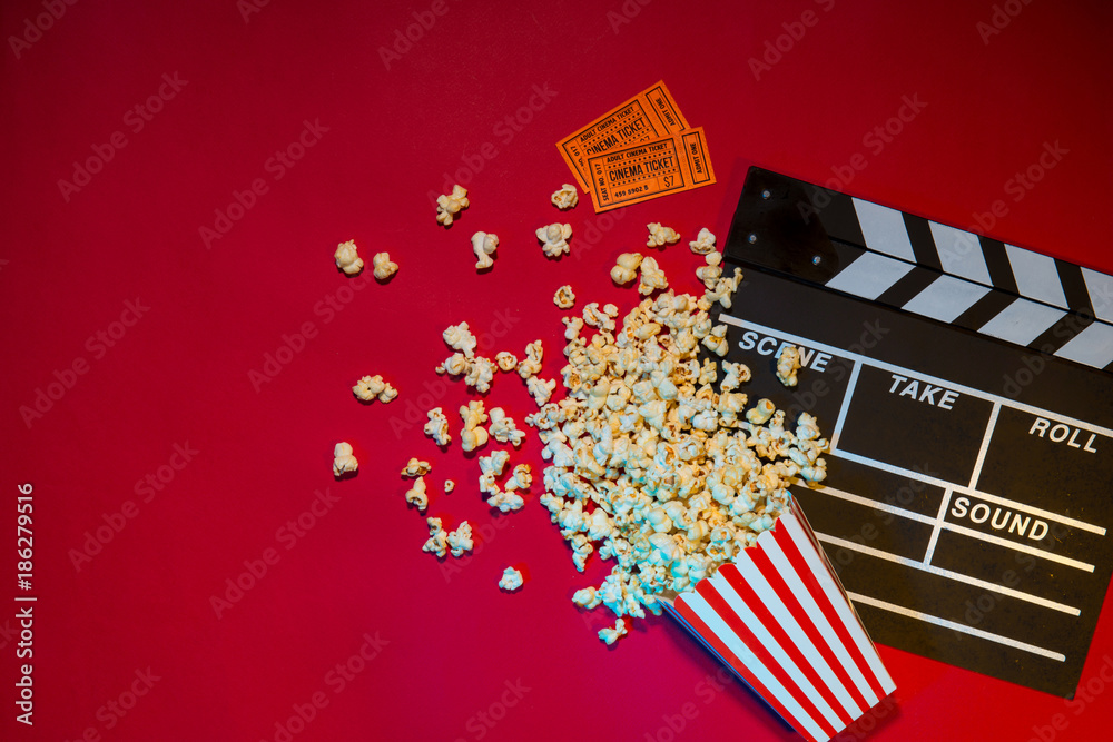 Movie tickets, clapperboard, pop corn on red background