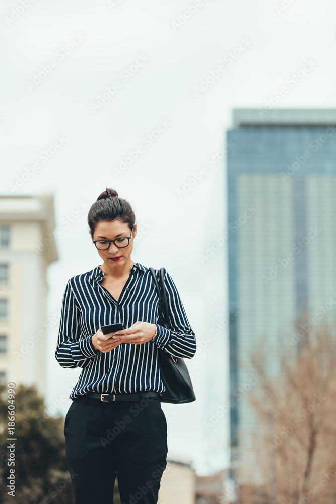 女商人在户外行走并使用手机