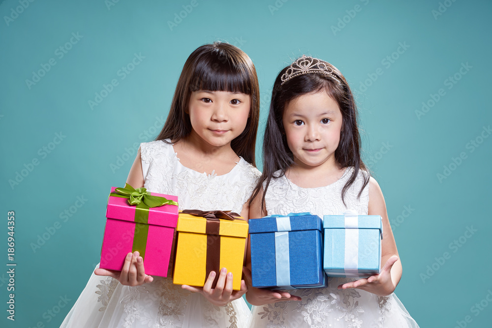 Portrait of two little asian beautiful girl holding four present box on vintage blue background .