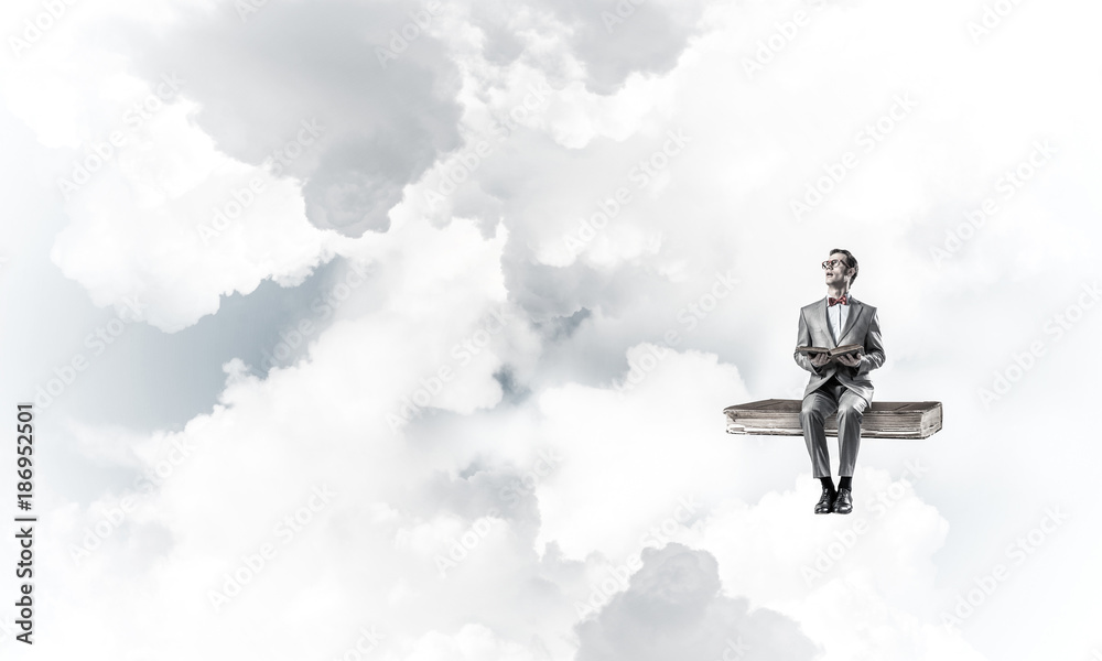 Young businessman or student floating in blue sky and studying t