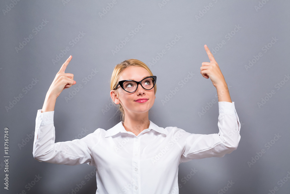 Young woman reaching and looking upwards on a solid background