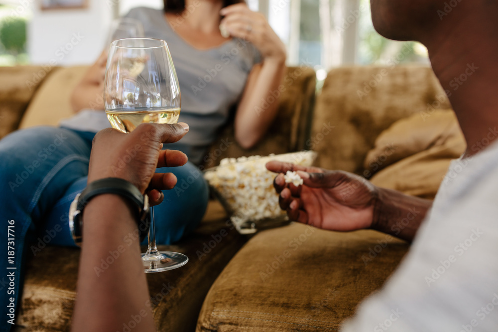 Couple at home drinking wine and eating popcorn