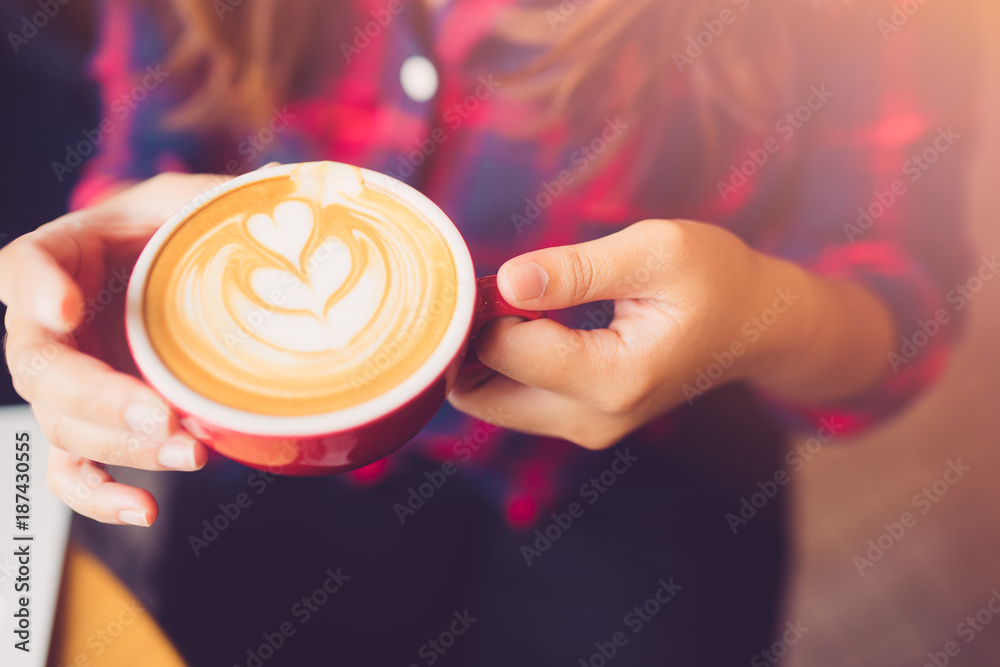 Coffee latte art on woman hand in coffee shop in vintage color filter