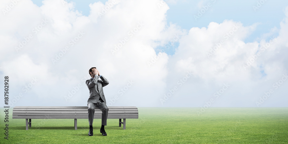 Young man in summer park on bench do not want to see anything