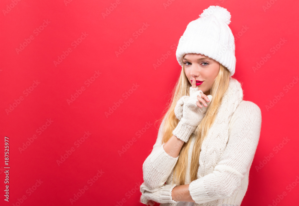 Happy young woman making a quiet gesture on a solid background