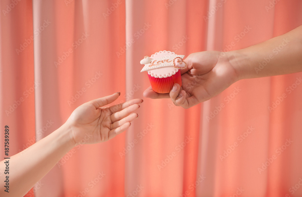 Valentine sweet love cupcake in hand on light background