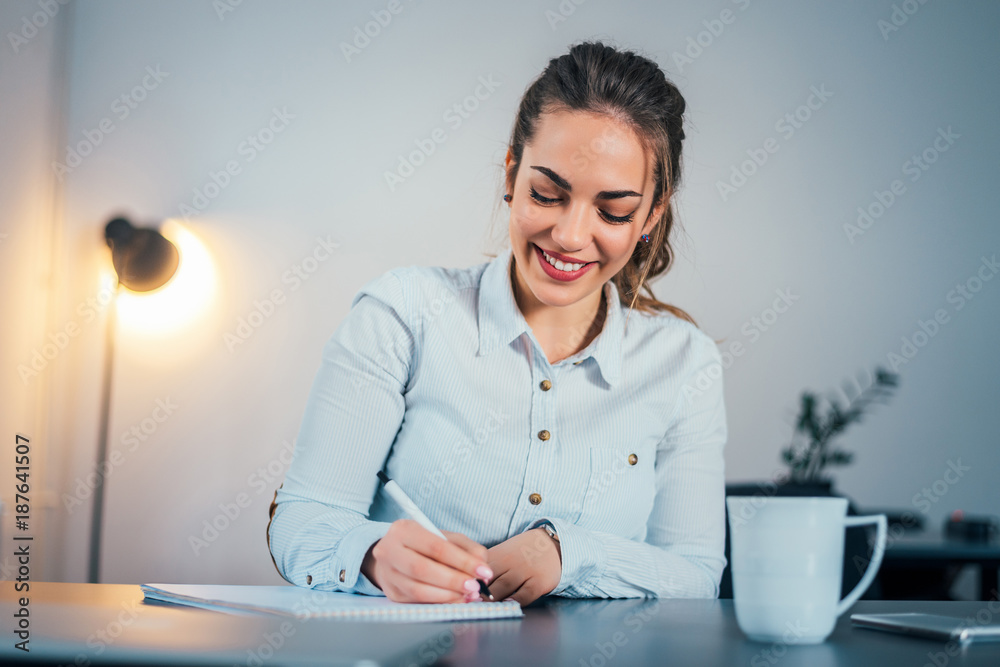 Young smiling woman writing notes.