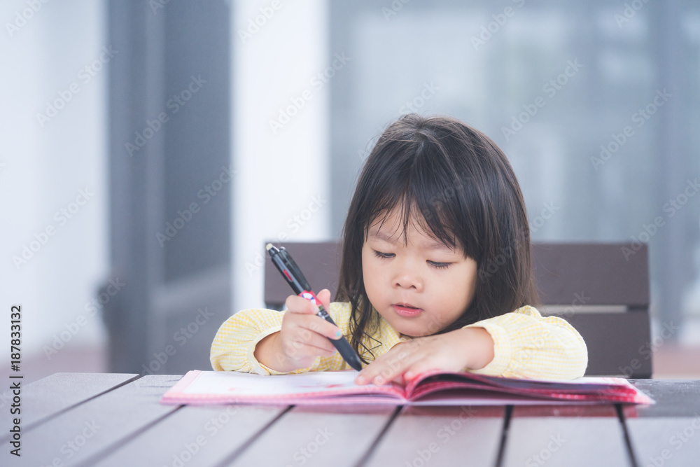 Cute little girl doing homework, reading a book, coloring pages, writing and painting. Children pain