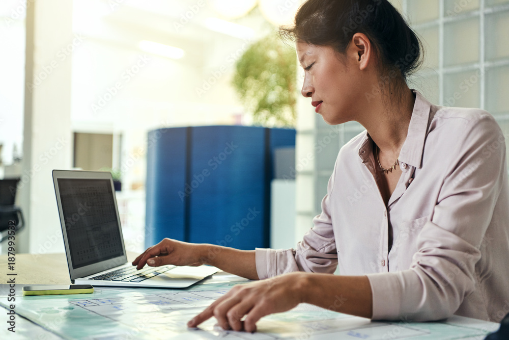 Focused Asian designer working at her desk in an office