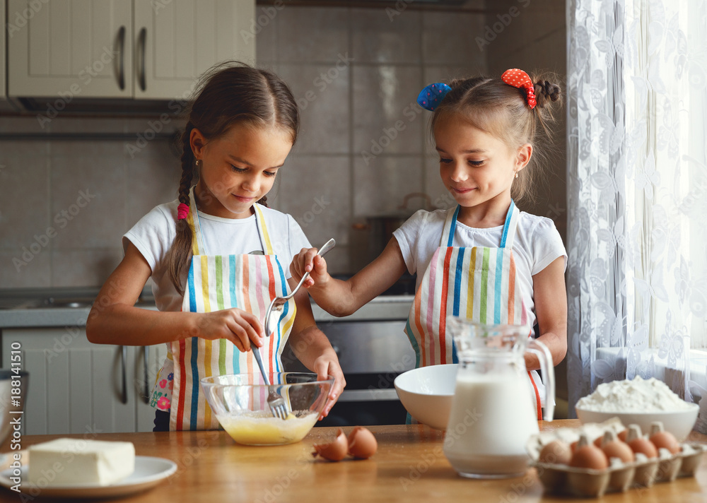 happy sisters children girls bake cookies, knead dough, play with flour and laugh