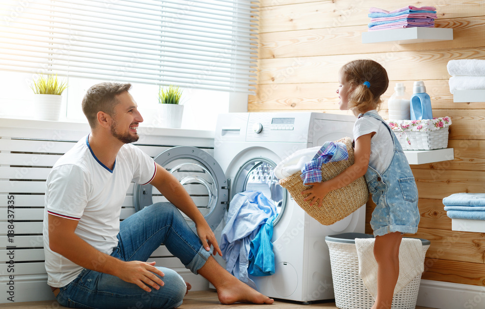 Happy family man father householder and child   in laundry with washing machine