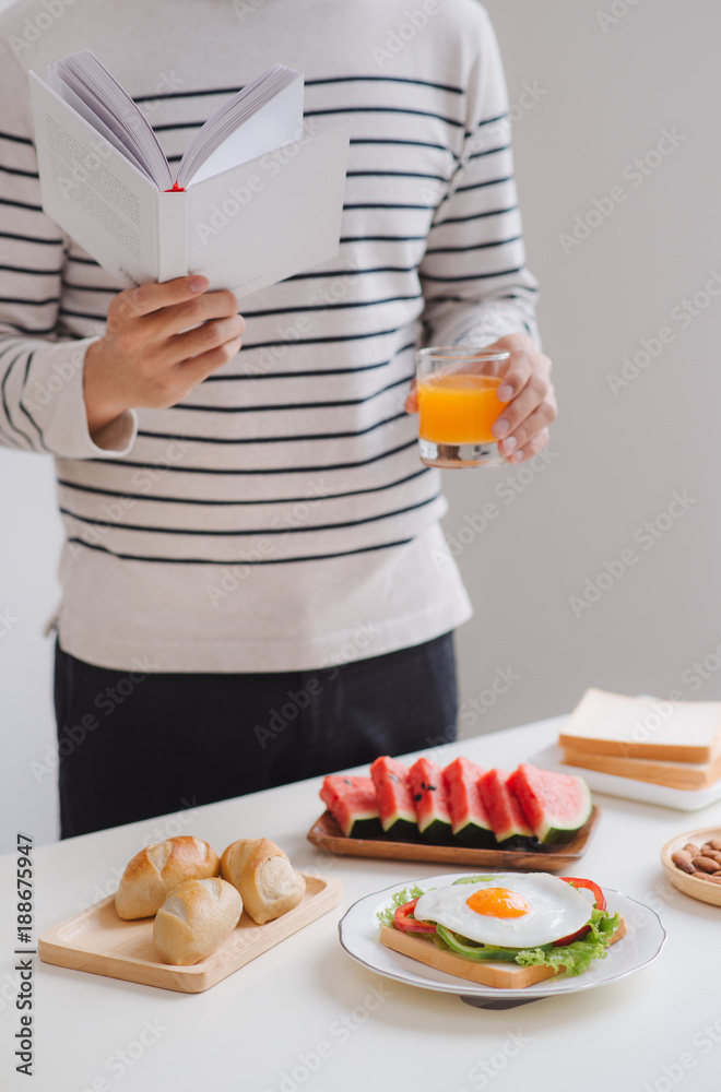 一个男人早上在家吃早餐看书。