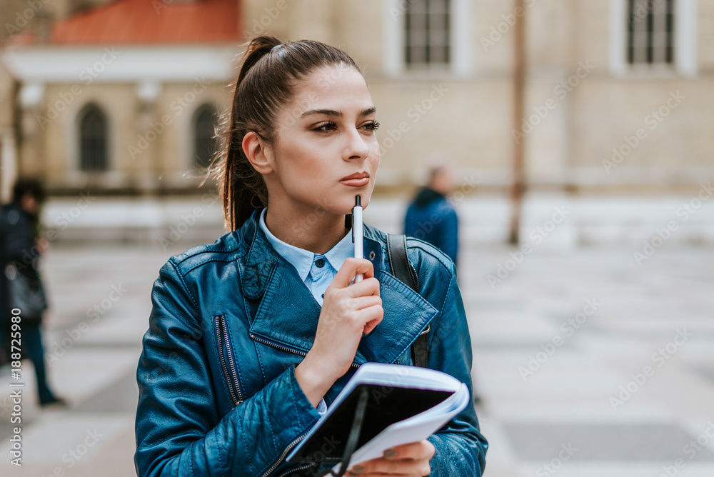 Daydreaming attractive woman taking notes.