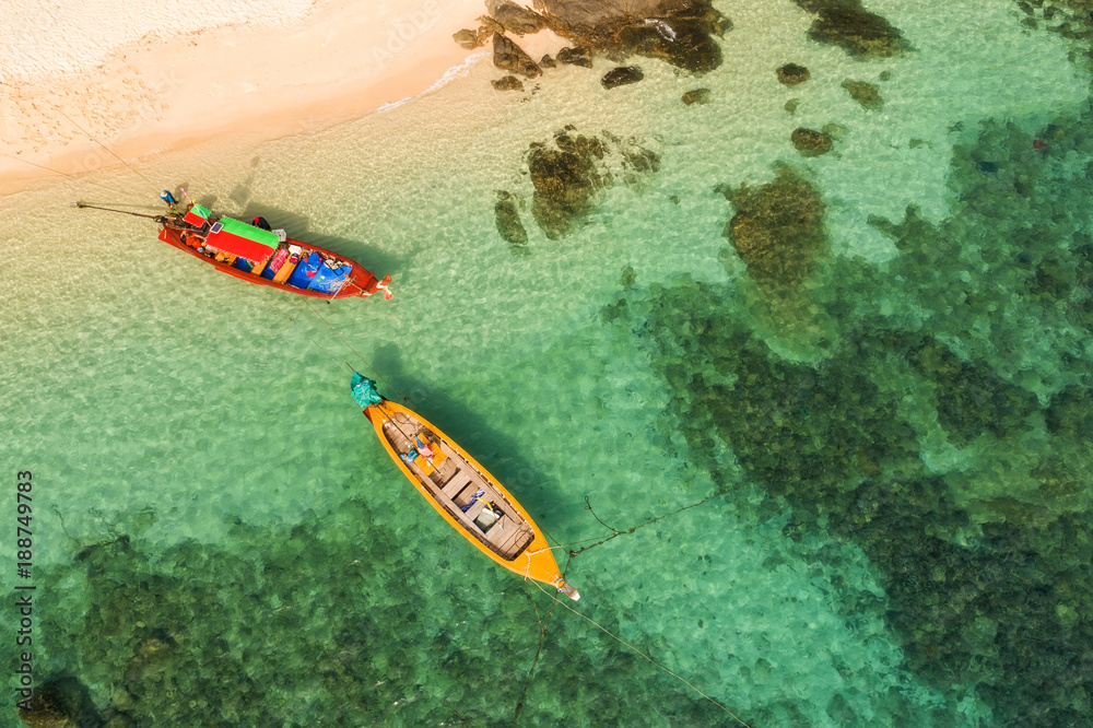 Drone flying under the amazing tropical bay with clear water, white beach and traditional longtail b