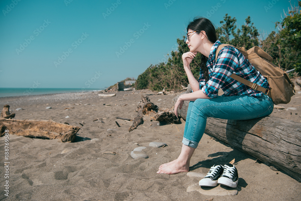 漂亮的徒步旅行者坐在木头上脱鞋