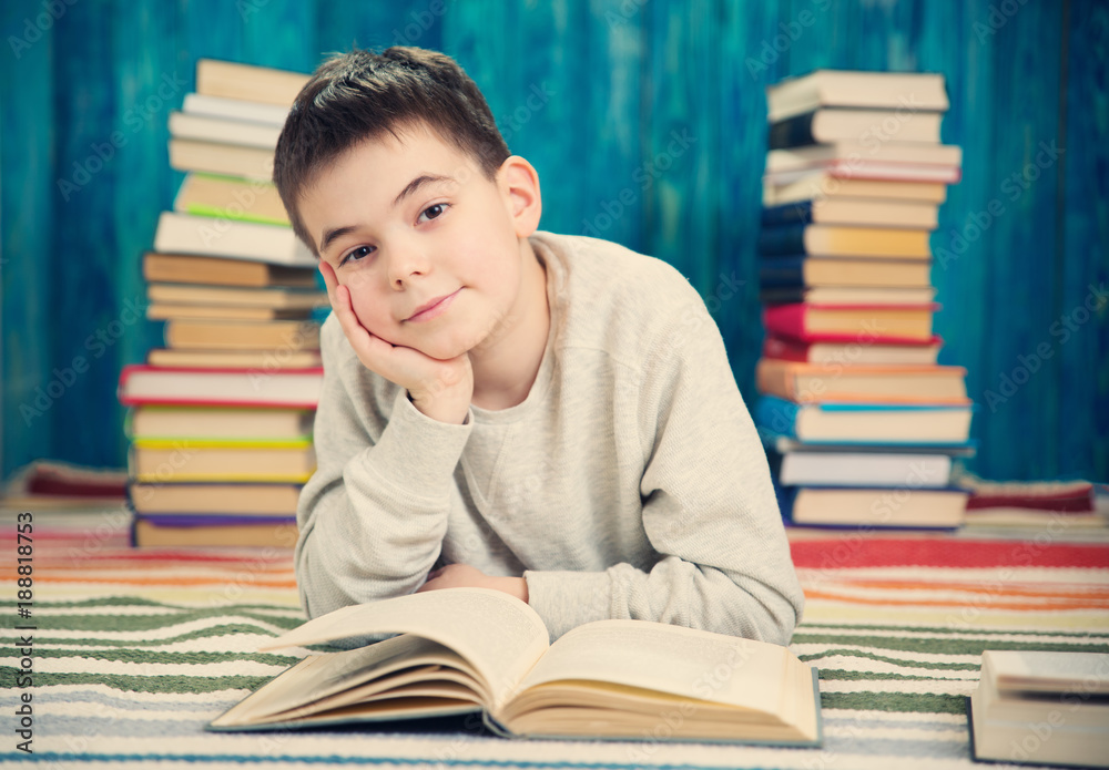 eight years old child reading a book at home. Boy studying at table on blue background