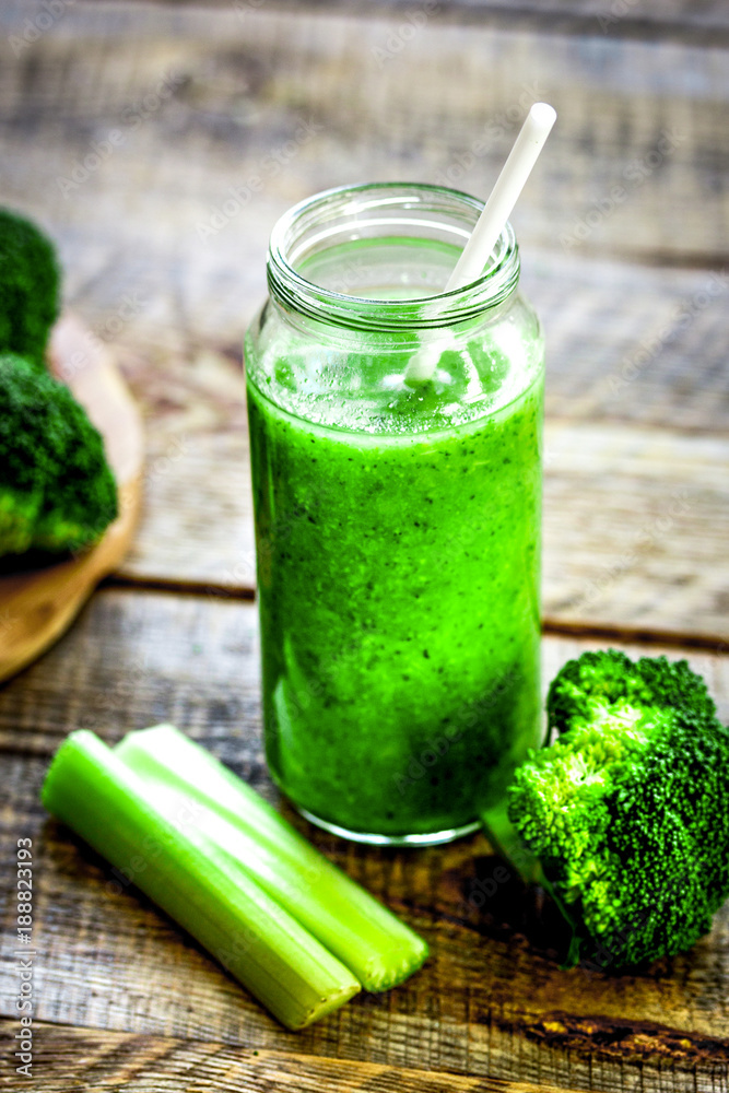 Green vegetable smoothie in glass at wooden background