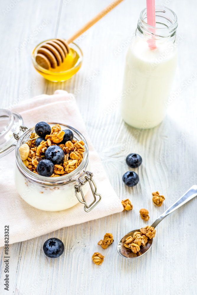 Homemade granola with blueberries in jar on white kitchen backgr