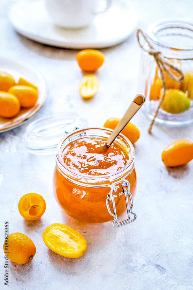 kumquat on plate and jam in jar at gray background