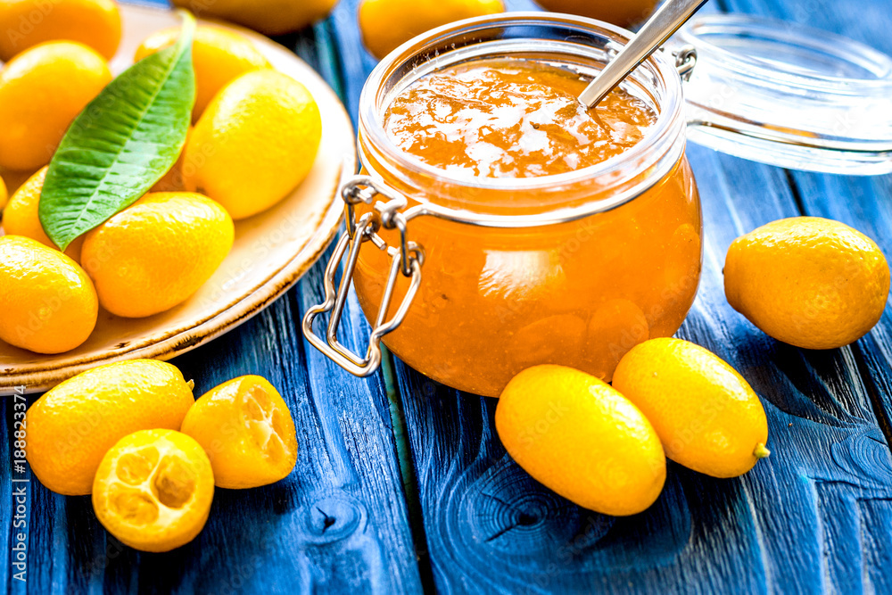 kumquat on plate and jam in jar at wooden table