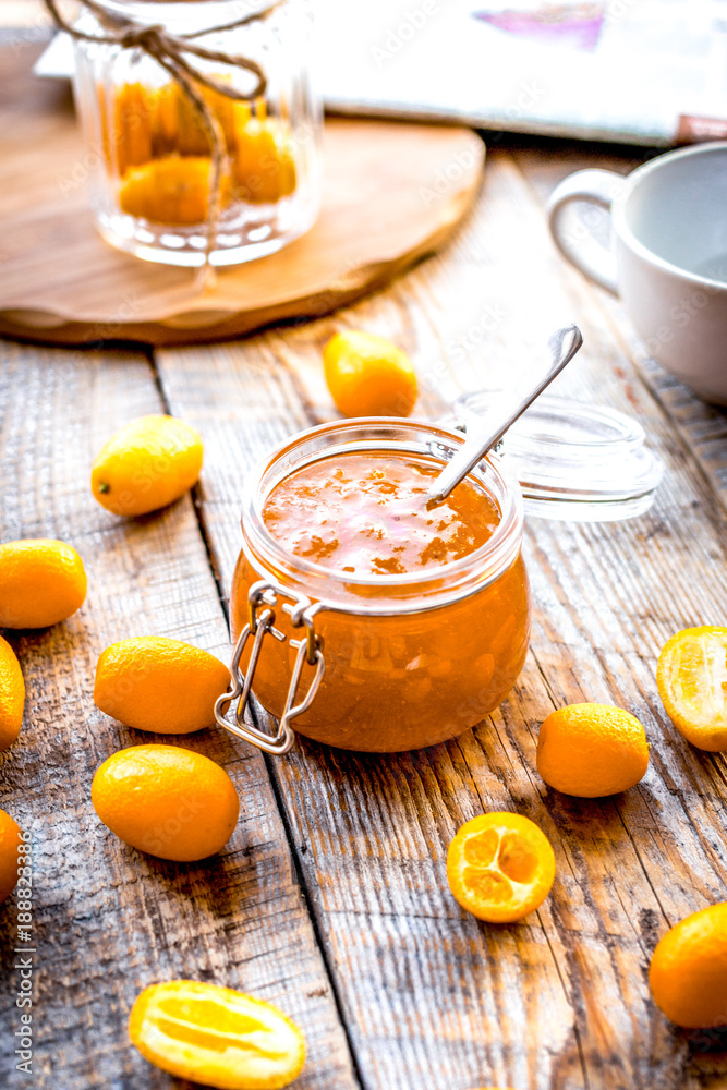 kumquat on plate and jam in jar at wooden table