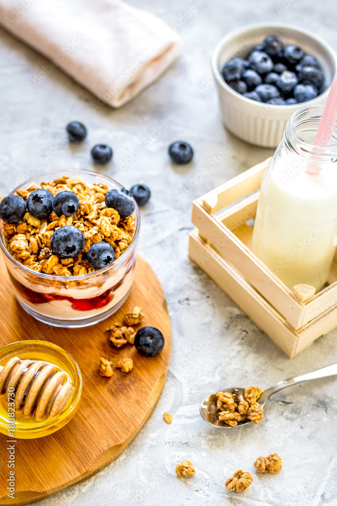 Morning granola with yogurt, honey and berries on white table