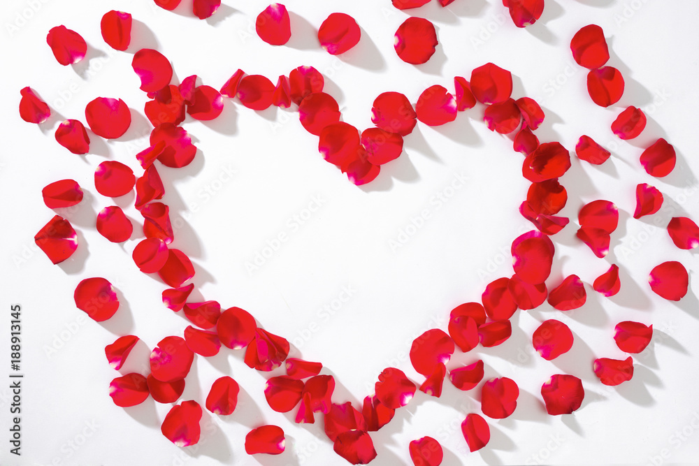 Heart of red rose petals on white background.