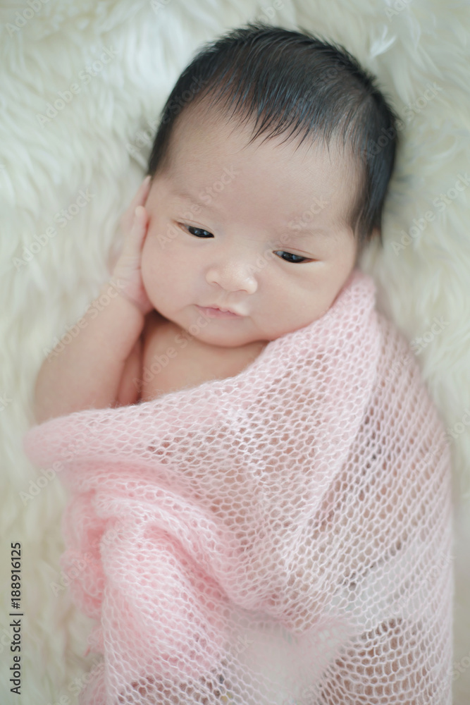 Lovely newborn Asian baby sleeping on furry cloth