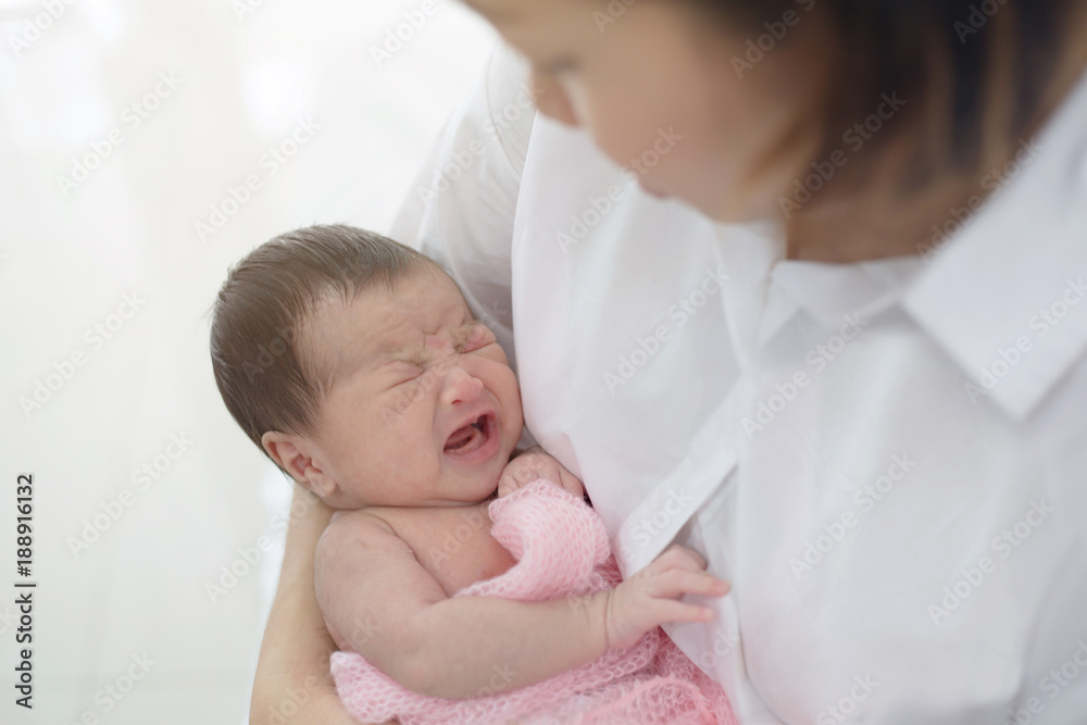 妈妈小心照顾她可爱的哭泣的新生儿