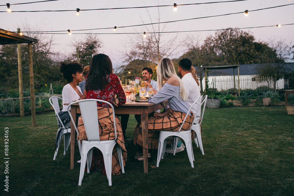 Group of friends having dinner in garden restaurant