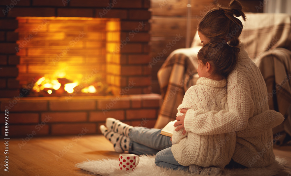 family mother and child hugs and warm on winter evening by fireplace.