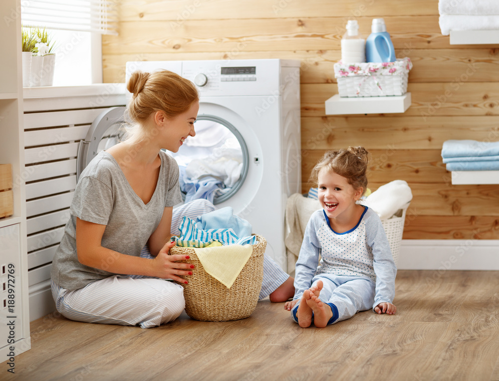 Happy family mother housewife and child   in laundry with washing machine