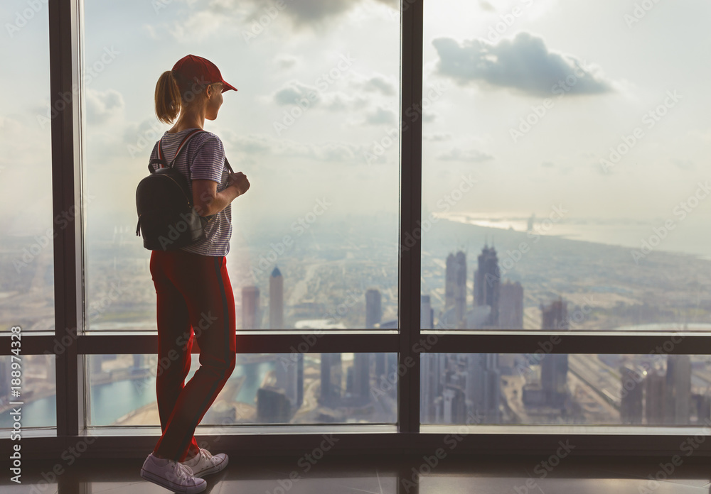 girl tourist at window of skyscraper of the Burj Khalifa in Dubai, United Arab Emirates, UAE