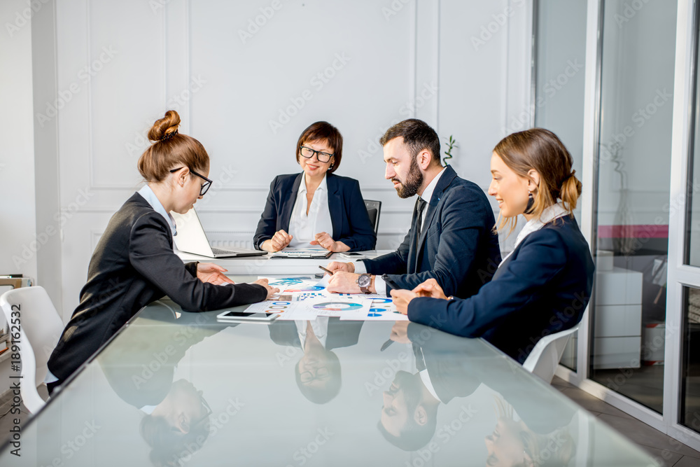 Business people working with charts and documents sitting at the table during the conference in the 