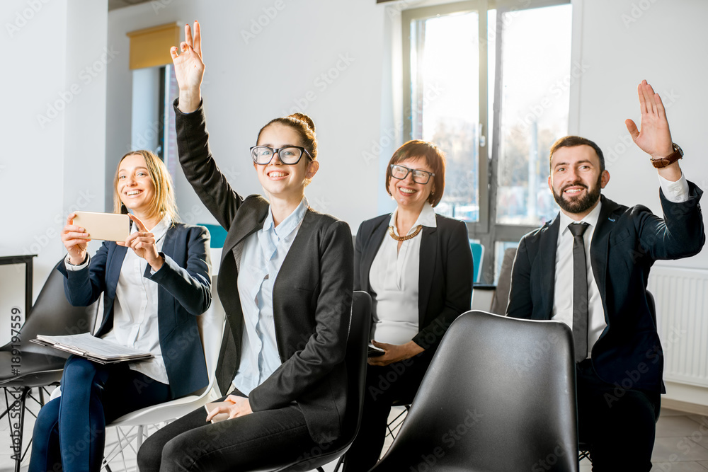 Business people sitting during the conference in the audience raising hands