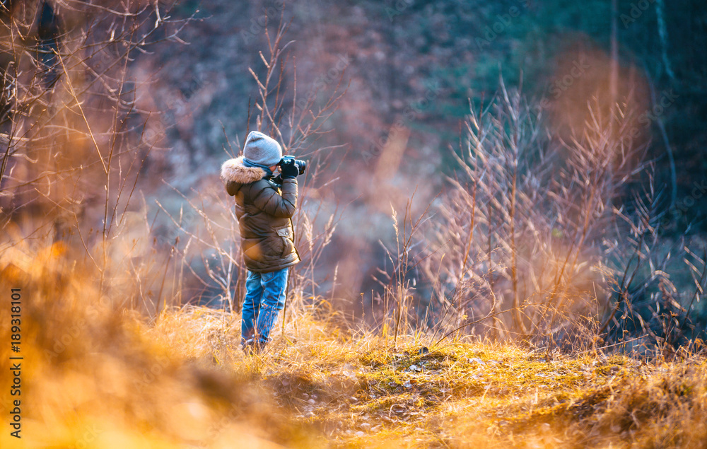 Boy using digital camera taking photo in the nature, hobby concept