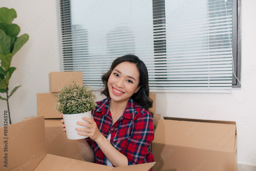 Portrait of happy woman during moving home  carrying carton boxes