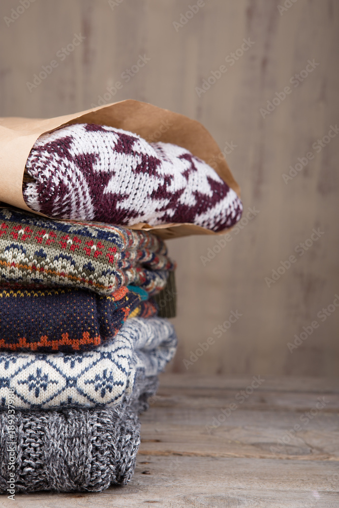 Pile of knitted winter sweaters on wooden background