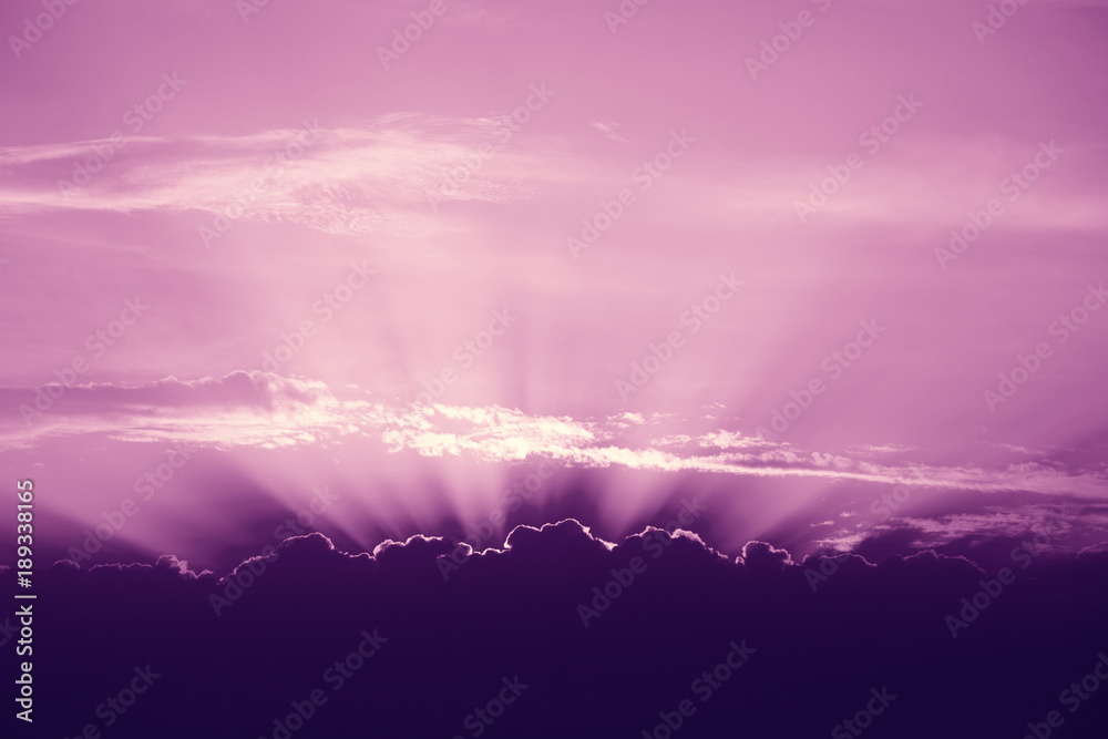 Beautiful violet sky with sun rays and clouds.