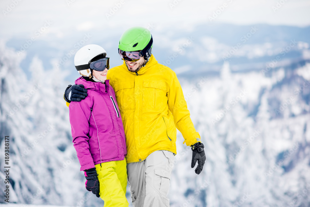 一对年轻快乐的单板滑雪运动员穿着五颜六色的运动服站在一起的肖像