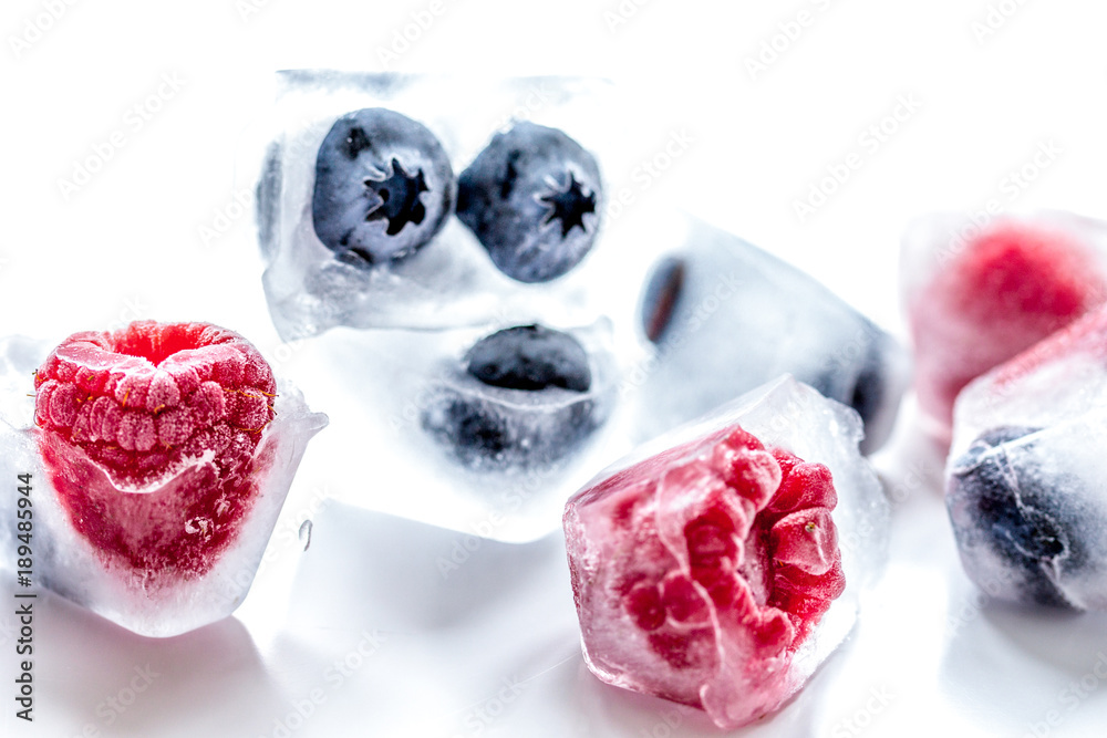 Ice cubes with frozen berries on white background