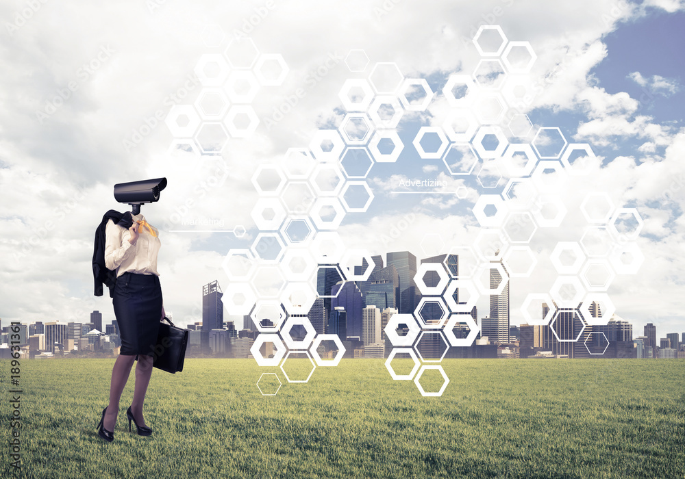 Camera headed woman standing on green grass against modern citys