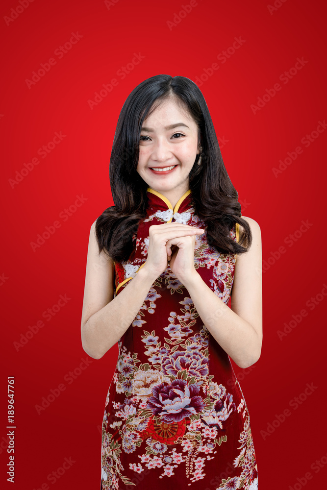 An Asian girl in Cheongsam or Qipao dress is smiling and happy emotion to you in Chinese New Year fe