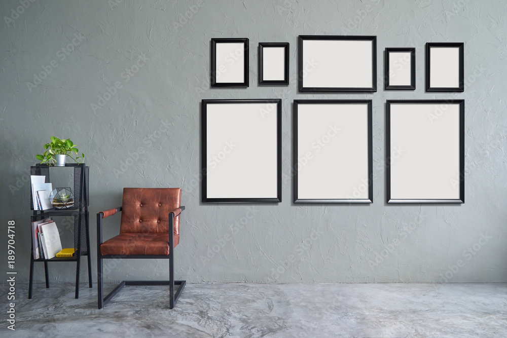 Loft style interior design  with eight empty picture frames, brown armchair and iron bookshelf .