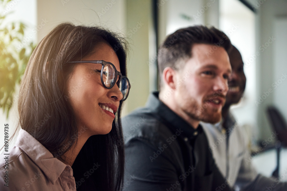 Diverse office colleagues smiling while sitting together in an office